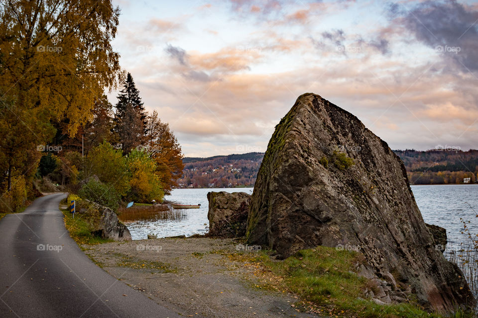 rocky shoreline of a small Lake in Sweden that is surrounded by autumn foliage
