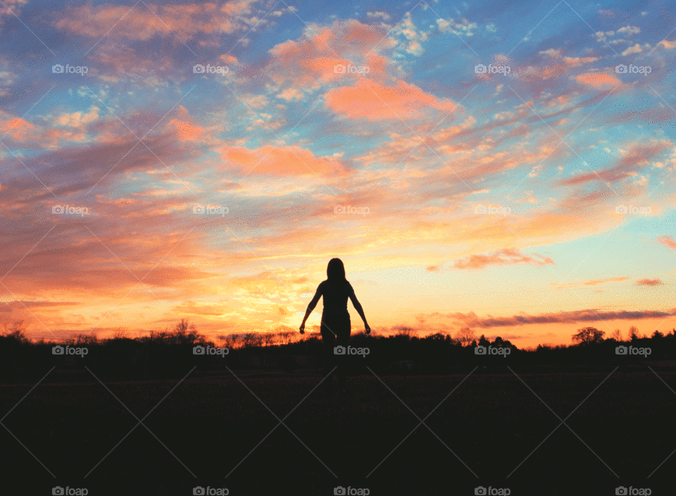 Silhouette of a person standing in front of a stunning sunset.
