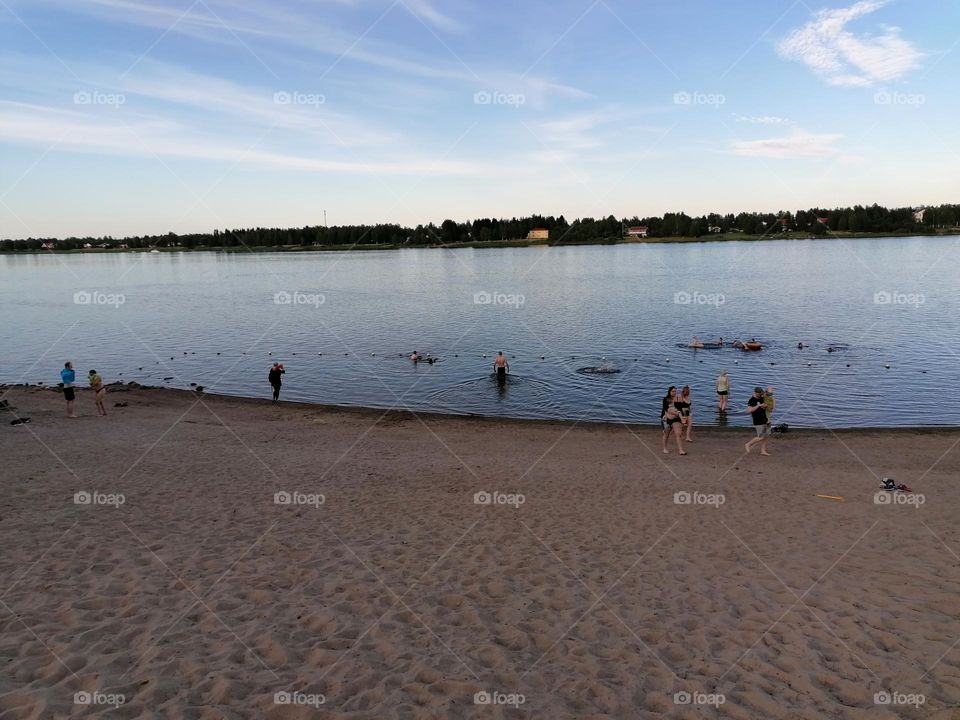 People swimming on a Finnish beach on a warm summer day