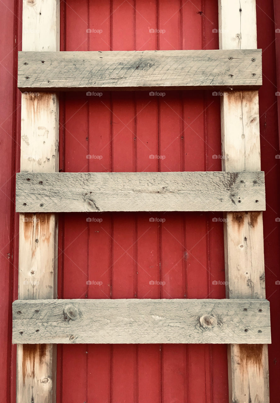 Wooden ladder against a red barn