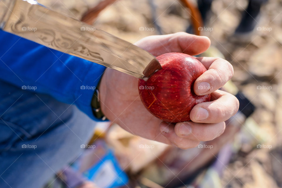 man cuts an apple with a knife, a red apple in the hands of a man, cut a red apple with a knife