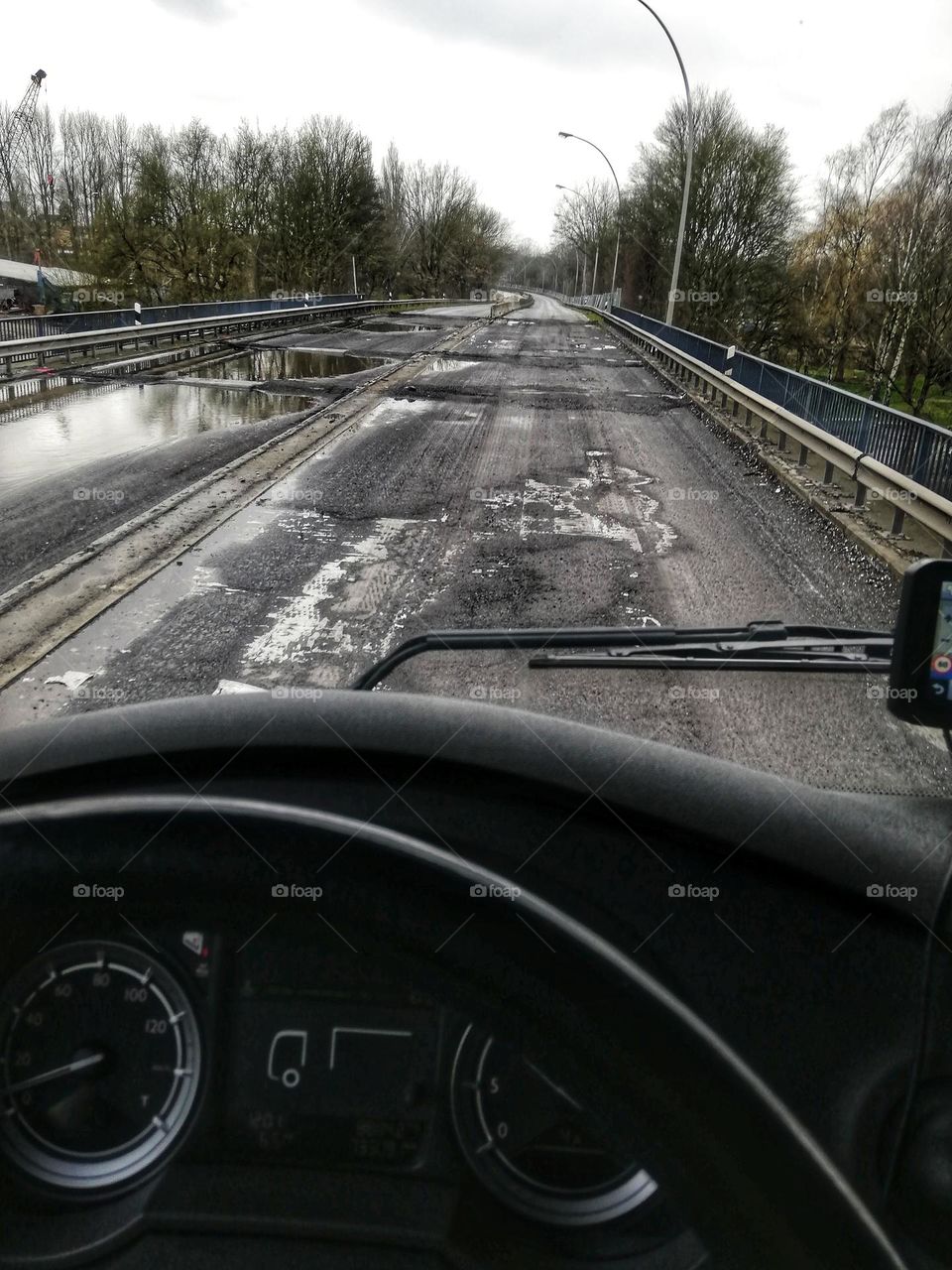 Broken road after winter. Bridge under repair.