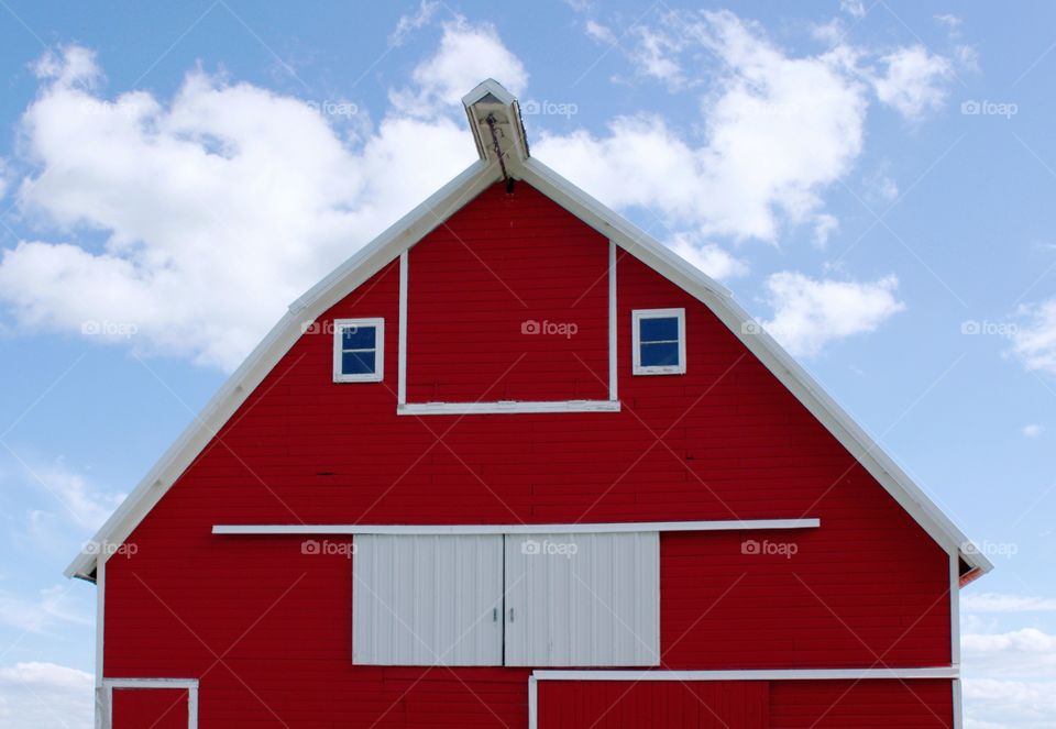 A big red barn against a beautiful summer sky