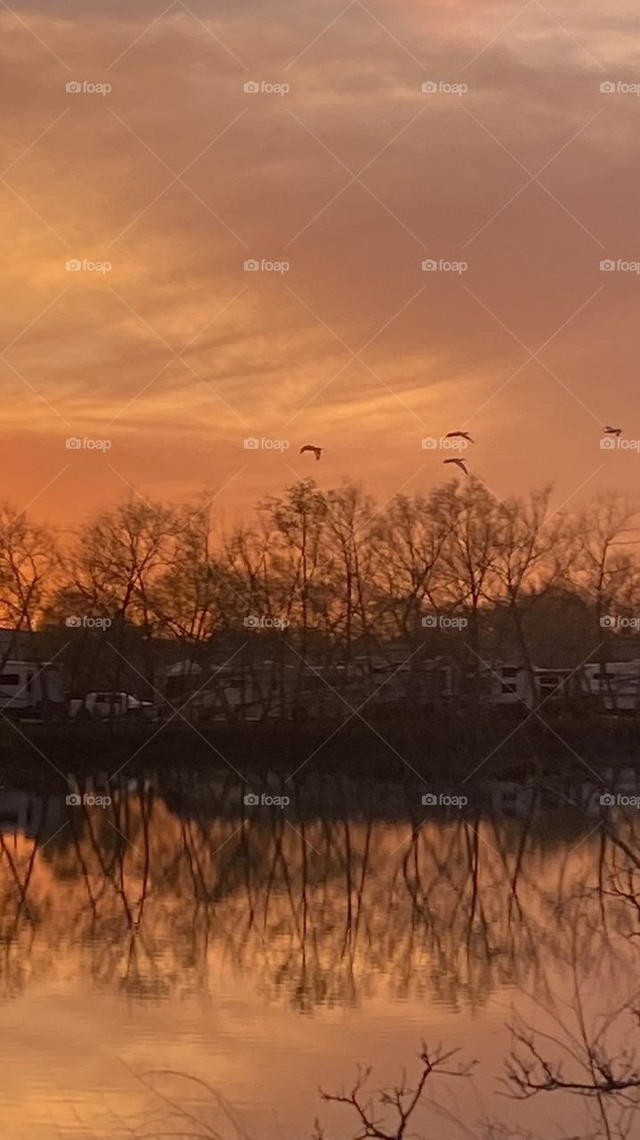 Heading Into Evening High Clouds Partly Separated parting letting in blue sky. Sun glowing with Reflections in water of Lake. Thin Yellow circle around Sun glowing while feathered clouds of Sun. Good clear picture with plenty of detail