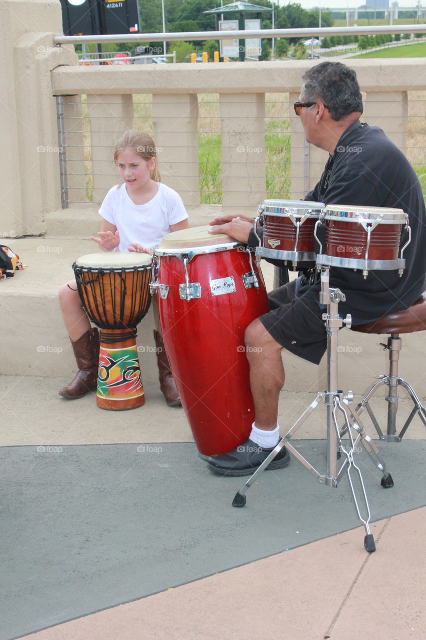 Little drummer girl. Girl and man playing drums on bridge