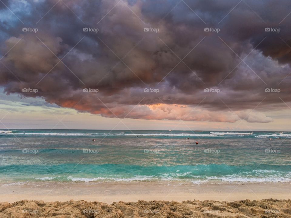 Colorful beach scene with storm clouds brewing at sunset. Oahu, Hawaii. 