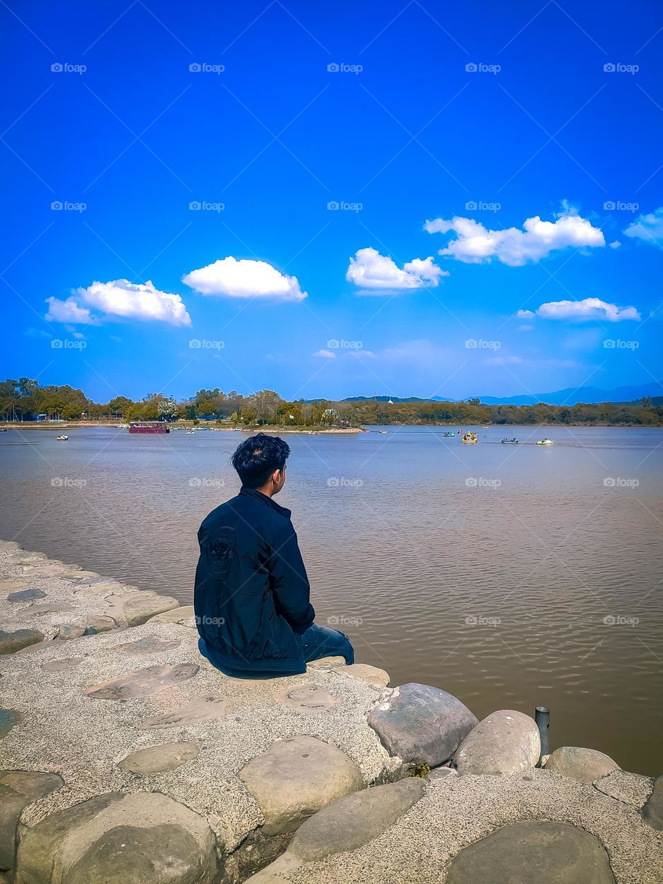 person sitting behind beautiful lake