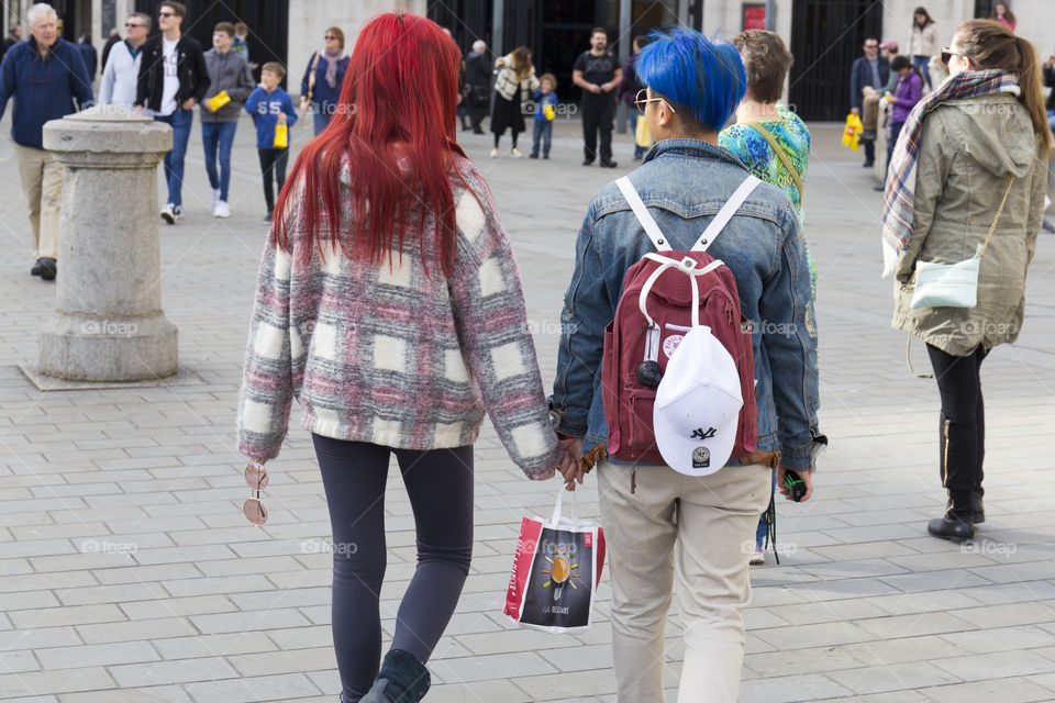 A couple with red and blue dyed hair holding hands 
