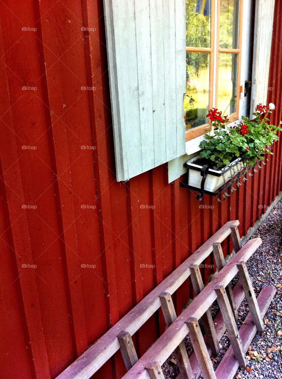 Red wooden house with shutters and flower box.