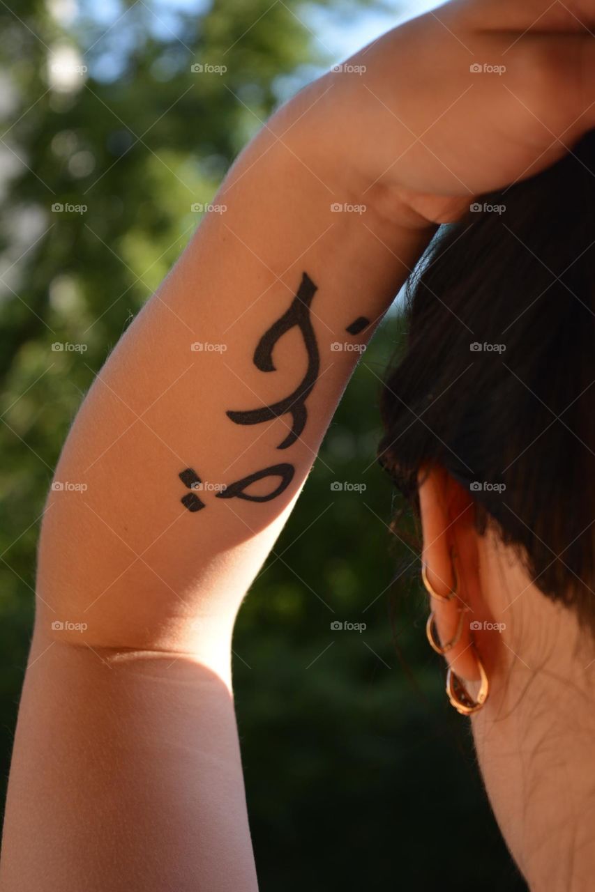 beautiful brunette girl in sunlight with tattoos on a hand