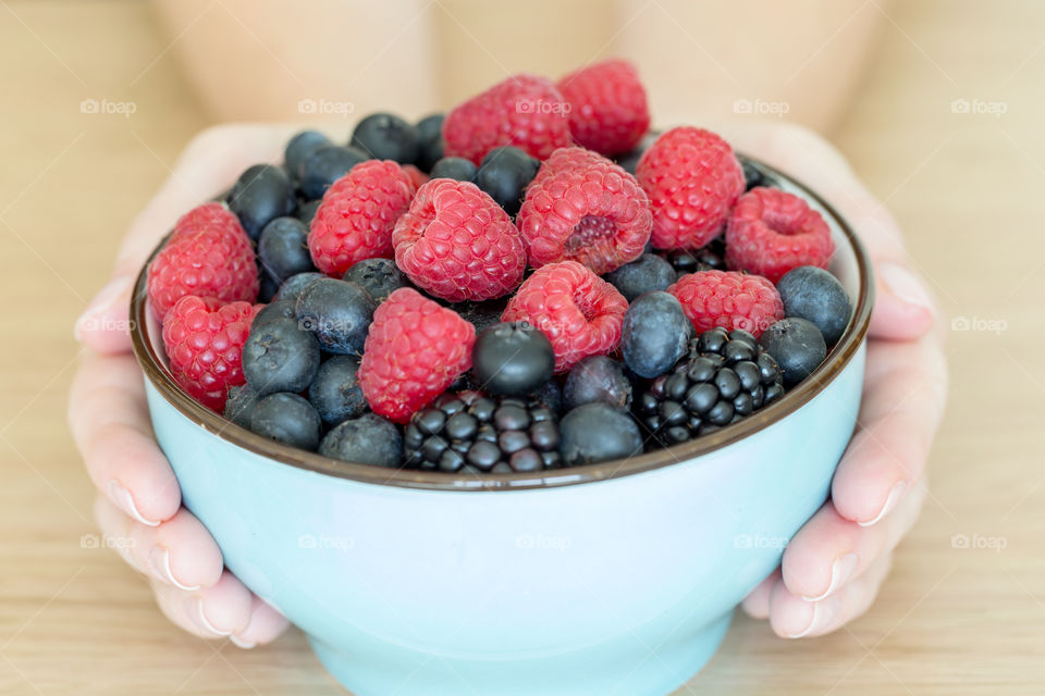 Bowl of summer berries in hands