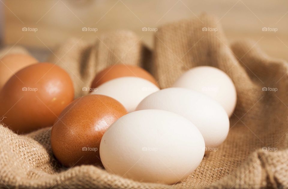 Fresh farm eggs on wooden and jute background