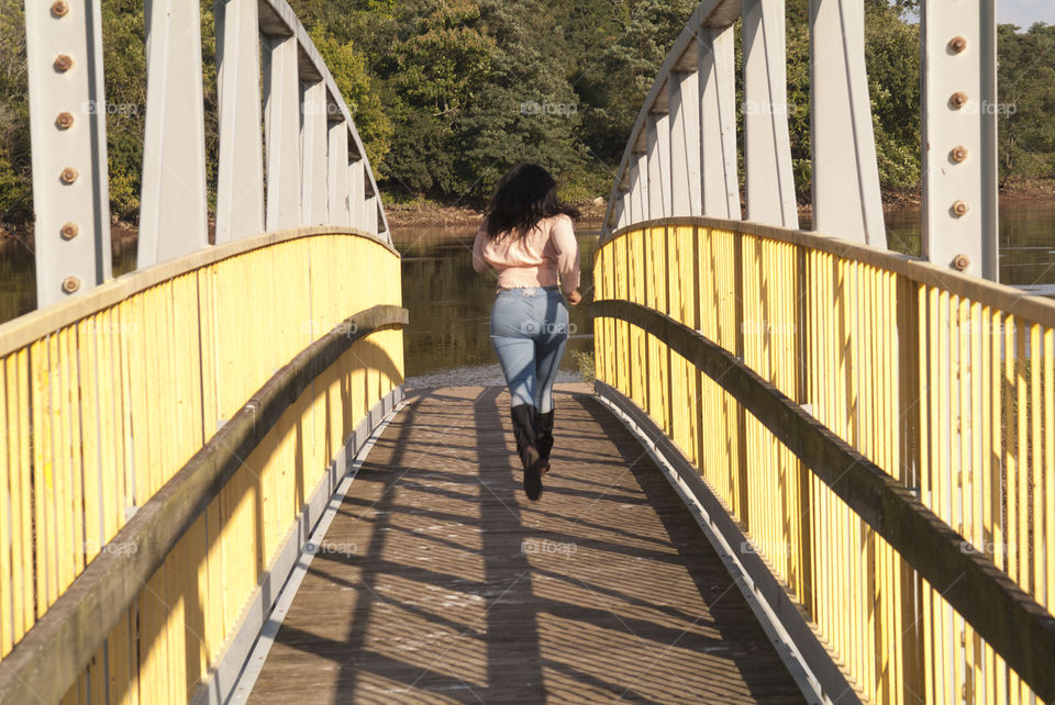 A young woman sprints across a bridge leading into the Raritan river of Boyd park in New Brunswick, New Jersey.