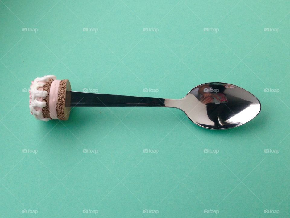 Spoon with cupcake on top isolated on green background 