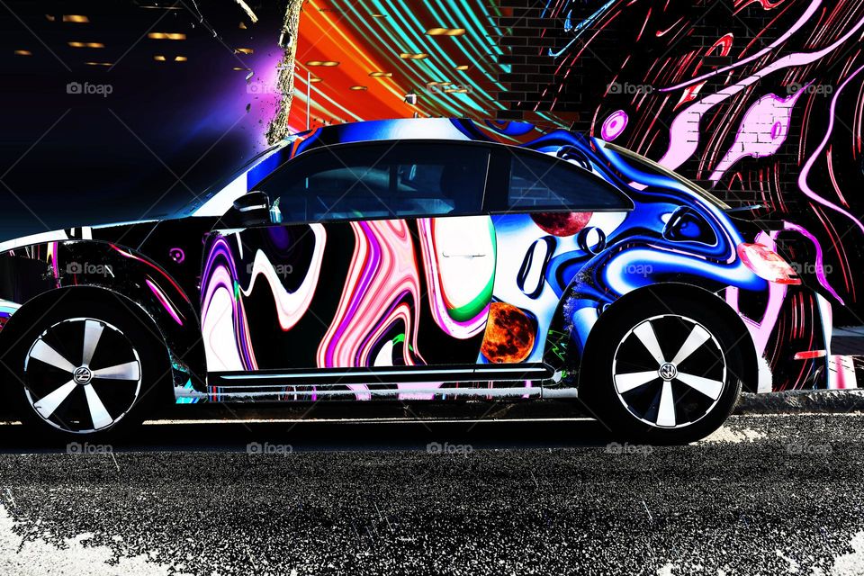 A Volkswagen Beetle parked on the street gets a funky new psychedelic makeover with all the colors on the spectrum.