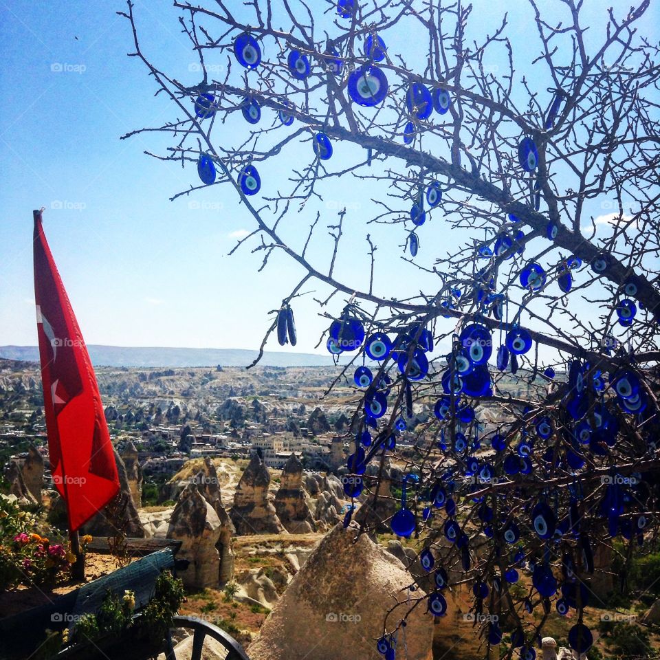 Morning view. Looking down on the spires of volcanic rock alongside a tree decorated with Turkish evil eyes in Cappadocia, Turkey