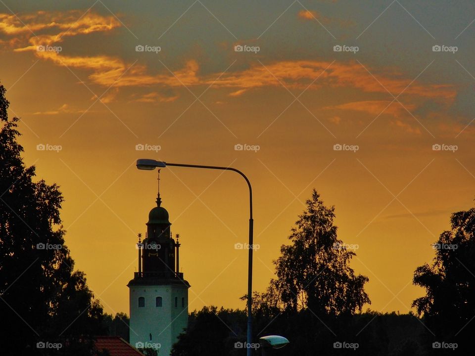 A sunset view in central Skellefteå, a snall city in the North of Sweden. A silhouette view marks the main church located in that place and contenplate a great mixed view of cemebt and trees.