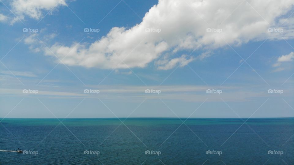 Above view gulf of Mexico. Tropical blue sea and blue sky with sun, clouds. clear water in the ocean. A blue, green, sea surface for background. View From above, flat lay. water horizon bird's eye.
