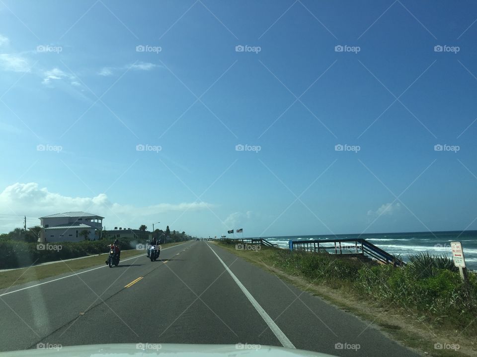 Motorcyclists riding their bikes on a Florida highway along the ocean.