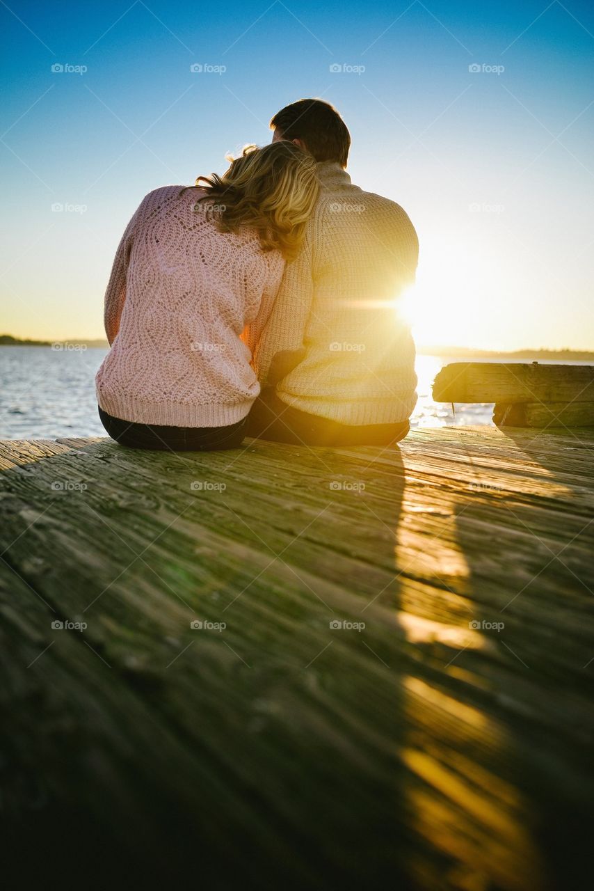 Rear view of a couple sitting on pier