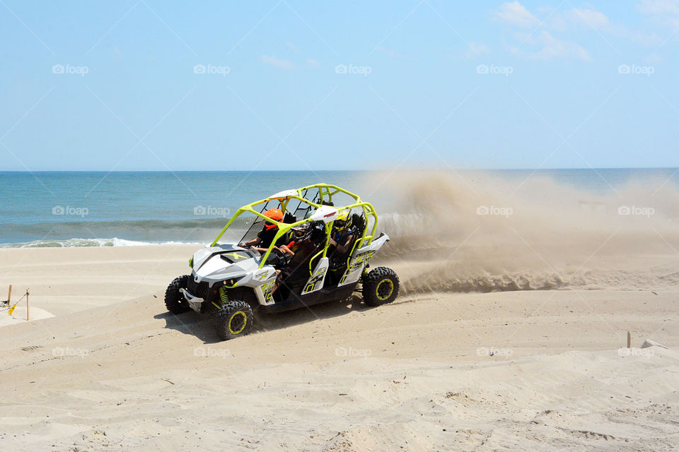 A recreational Jeep is seen driving on a sand dune by the ocean