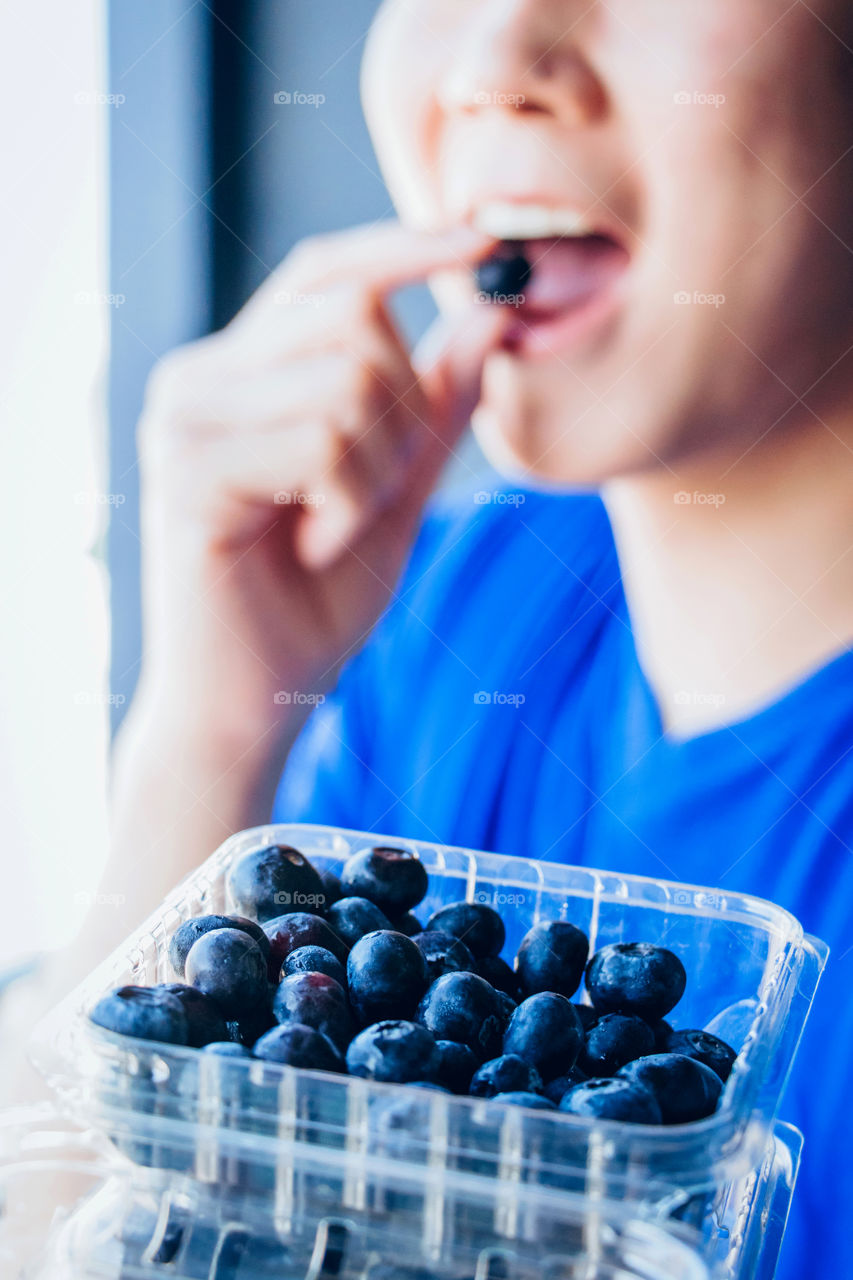 Healthy young man eating fresh organic blueberries 