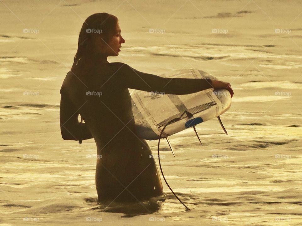 Sexy Surfer Girl. California Woman Entering The Pacific Ocean With Her Surfboard
