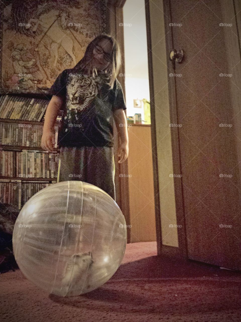Teenager girl with toy transparent ball standing at home