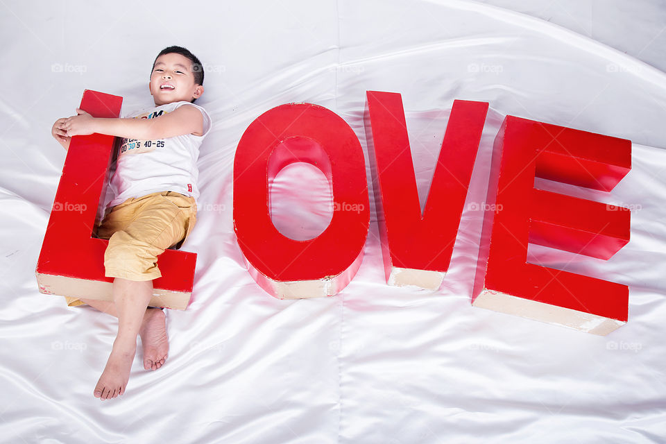 Asian boy lying on bed with text Love