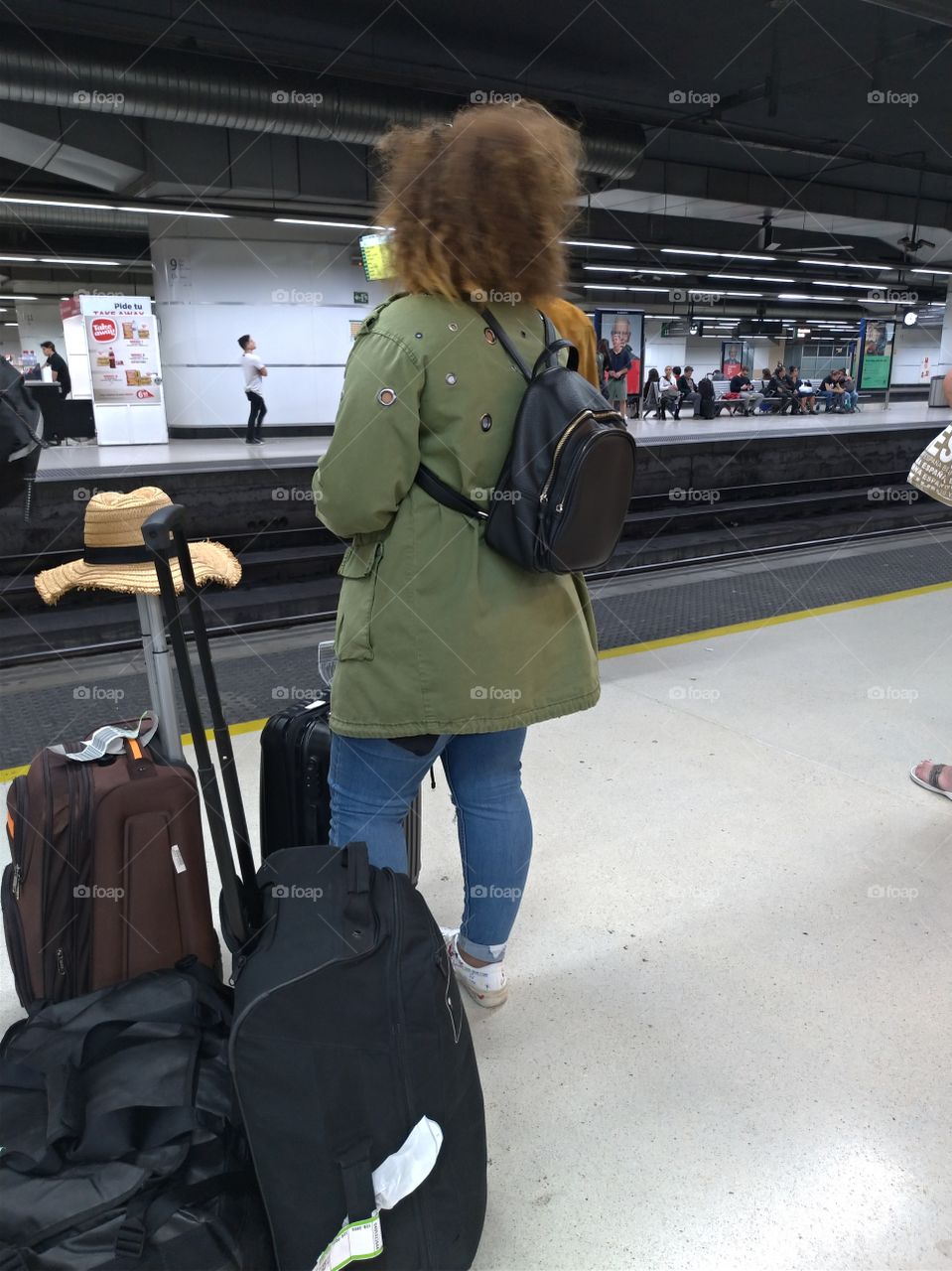 Una mujer esperando el tren con su equipaje
