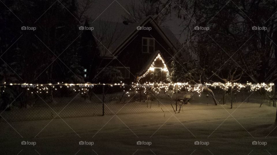 bright white Christmas lights on house in snowstorm