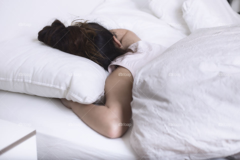 A lady sleeping under a white blanket 
