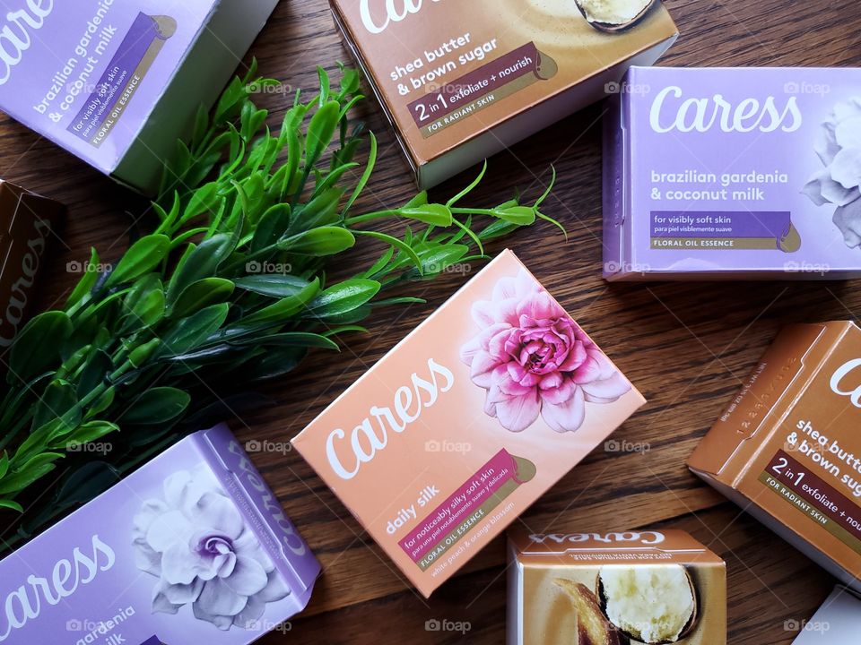 A variety of several of the new look Caress single pack soap bars on a wood surface accented by greenery.