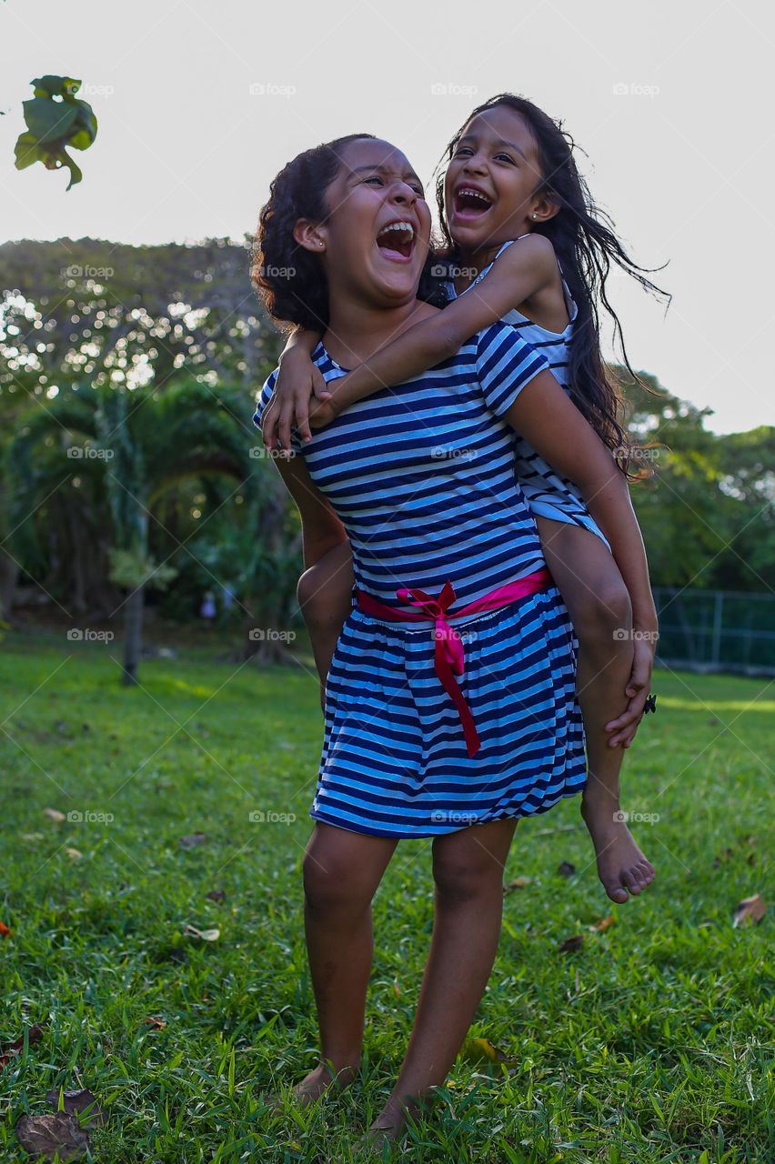 Two sisters having fun in the garden, girls smiling and playing 
