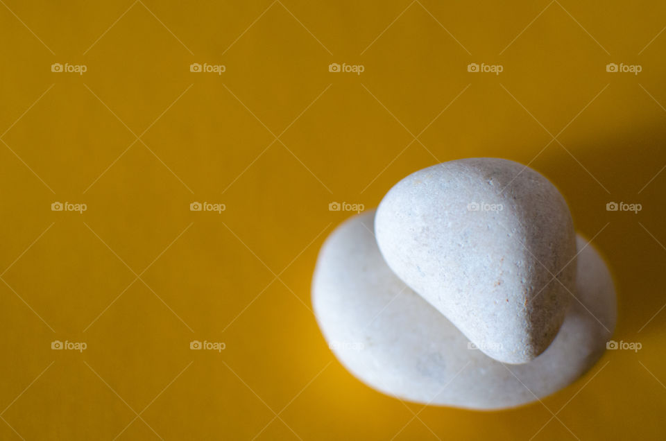 Stack of two white rocks on yellow background