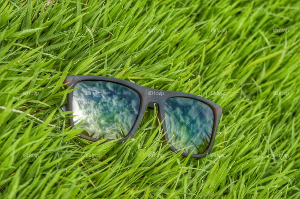 sunglasses in a brown frame lie on the green grass