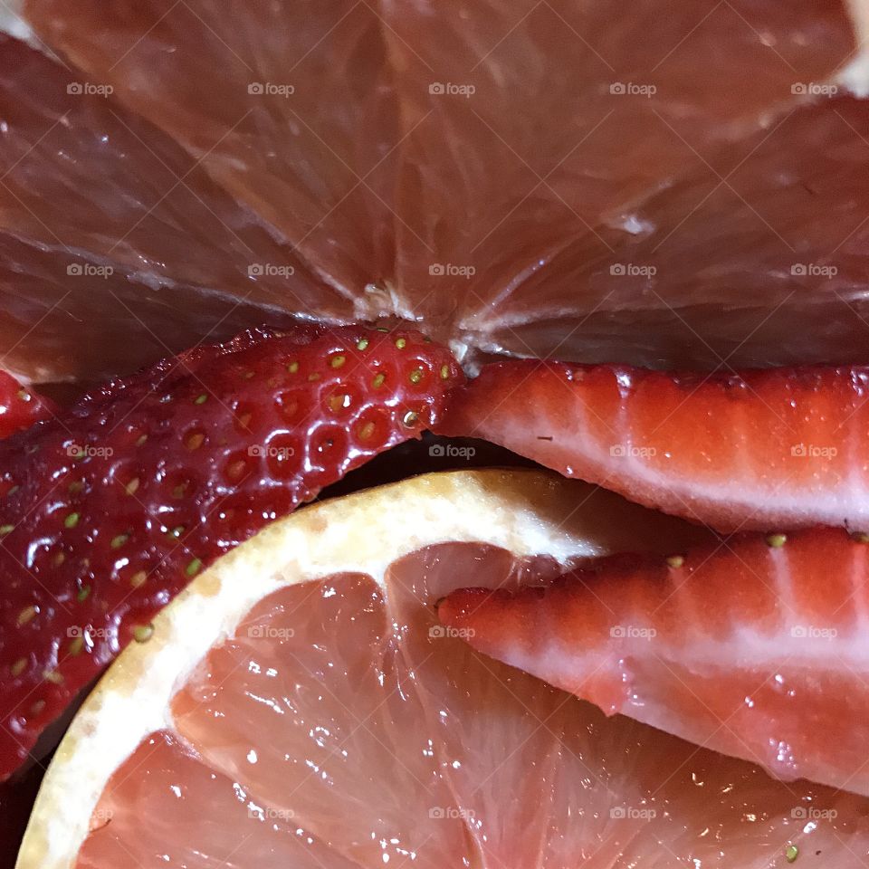 Details of freshly sliced grapefruit and strawberries for breakfast. 
