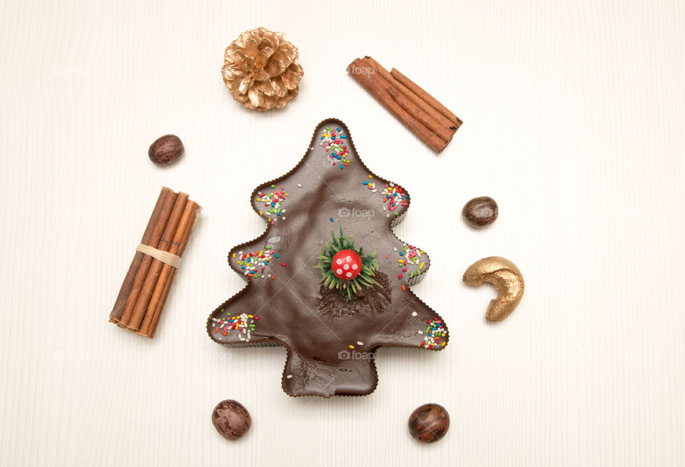 Composition Of Christmas Tree And Star Chocolate Muffin Cupcake, Pine Cone, Nuts And Cinnamon Isolated On White Background
