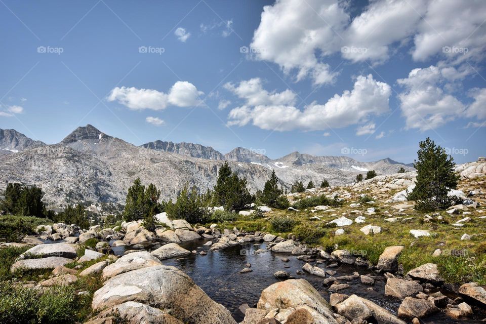 A rocky landscape with small pond are the foreground to the dramatic glacial divide in California