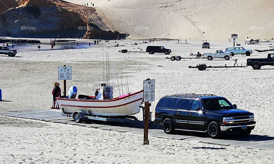 A Dory boat being towed out of the sea and through the sand. Dory boats are made to be drive. directly into the ocean without a ramp.