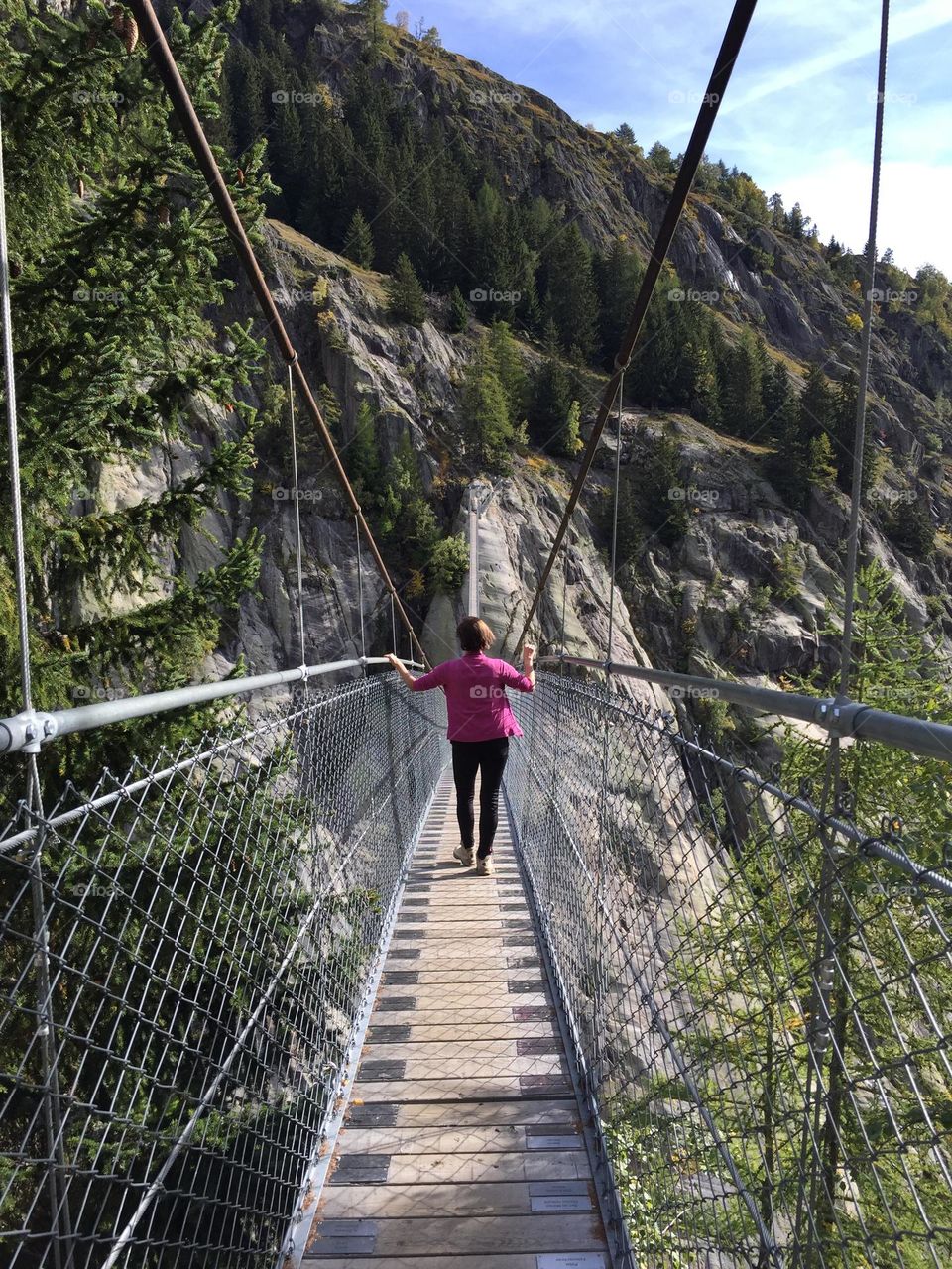 Balancing on a Suspension Bridge during a hiking Tour in the Swiss Mountains