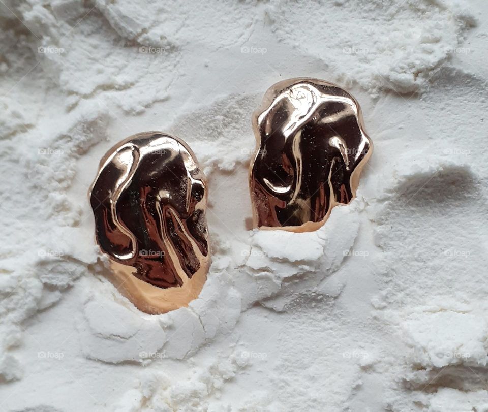 Gold earrings on a flour background