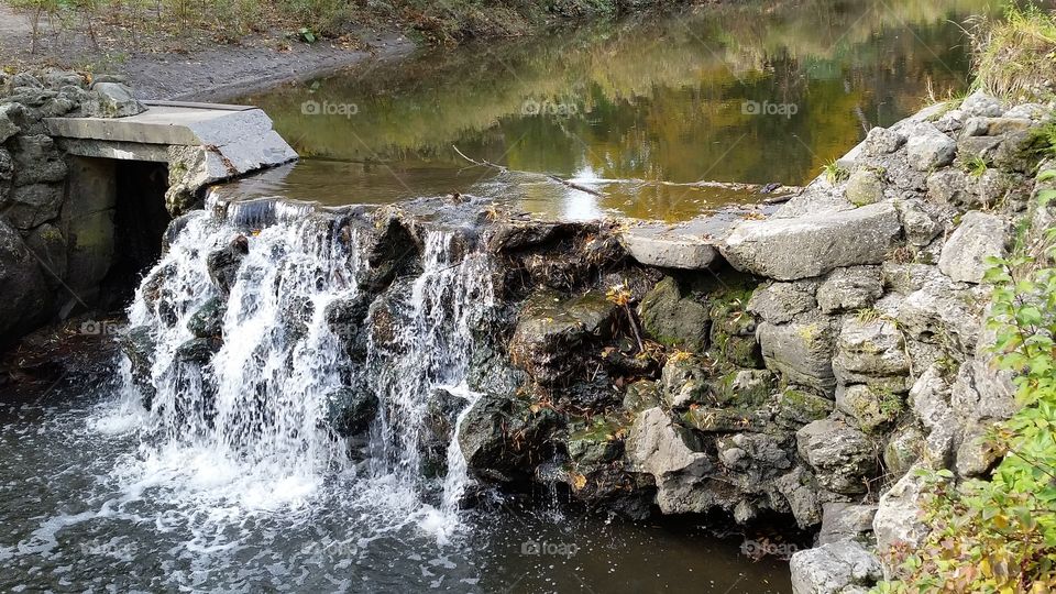 Water cascading over a low stone wall at the Botanical Gardens in Toronto, Ontario.