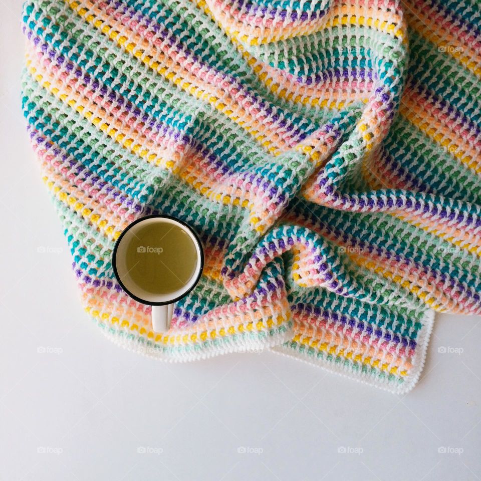 Colorful knitted plaid with a cup of tea on a white background, nobody 