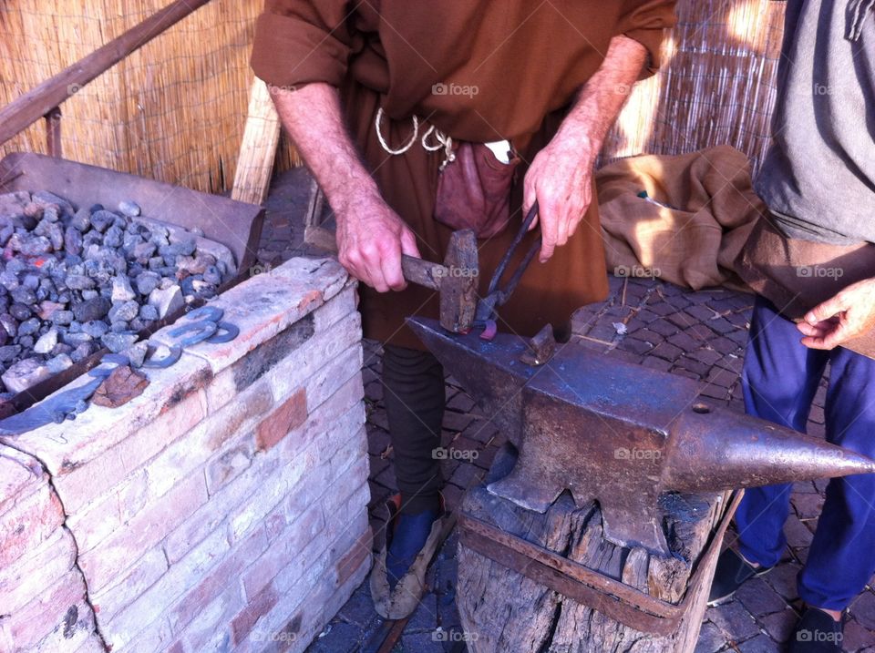 a blacksmith at work during a medieval representation in a street rional market