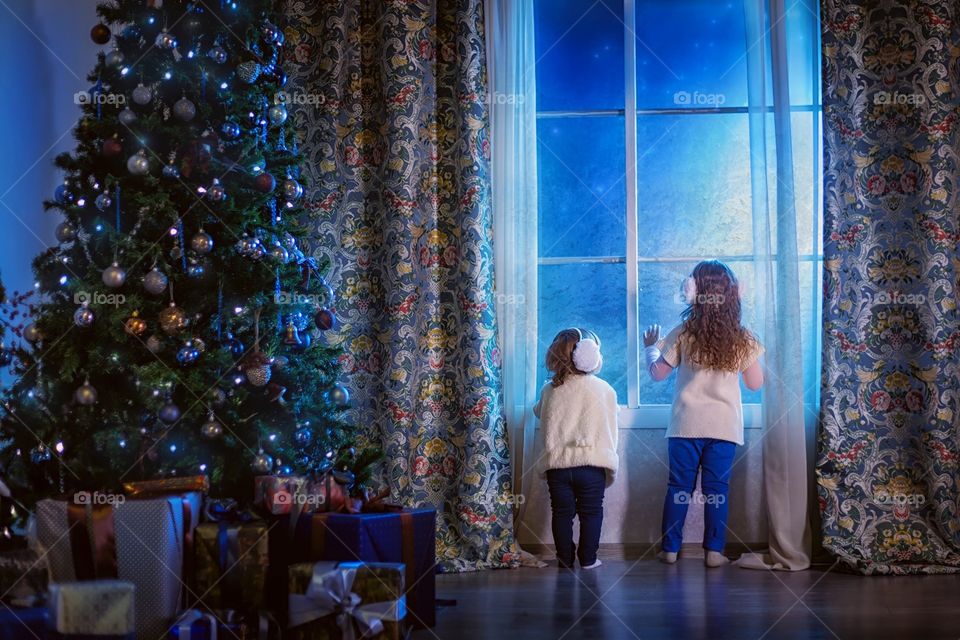 Little sisters waiting the Santa at Christmas Eve 