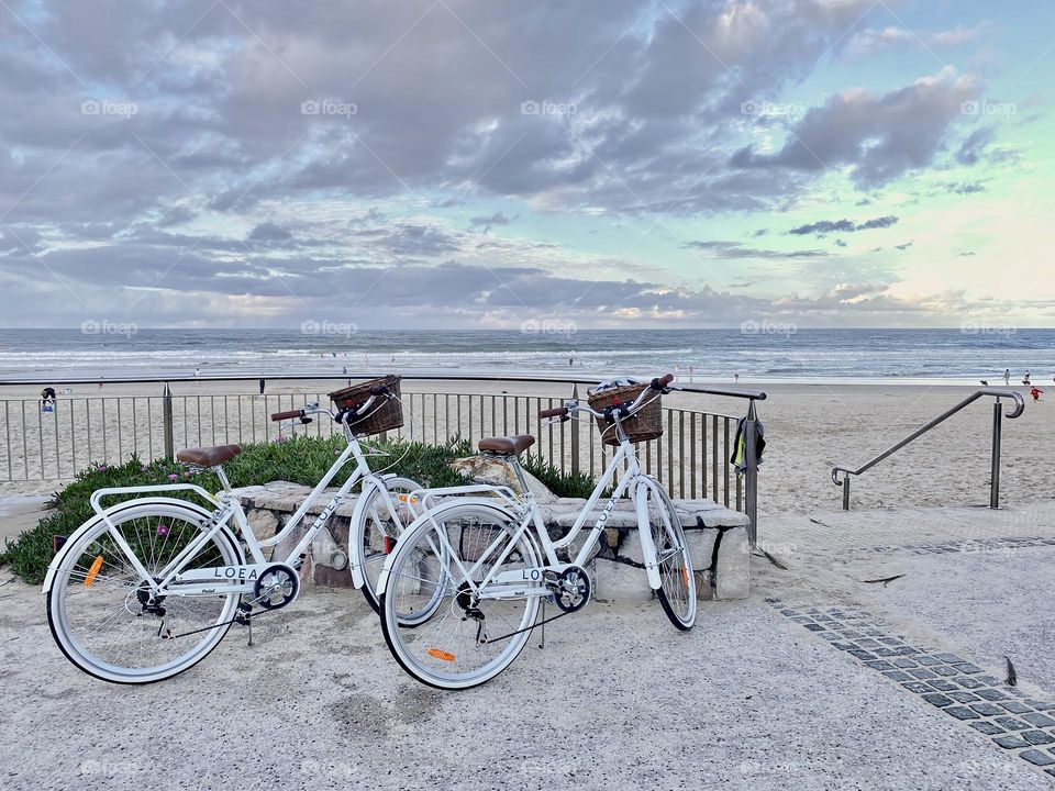 Two white bicycles near the beach 
