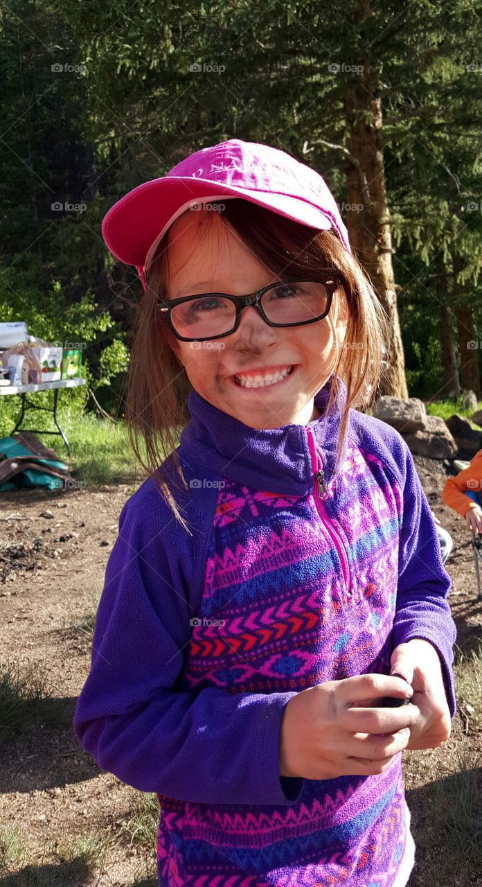 Young girl camping with dirty face.