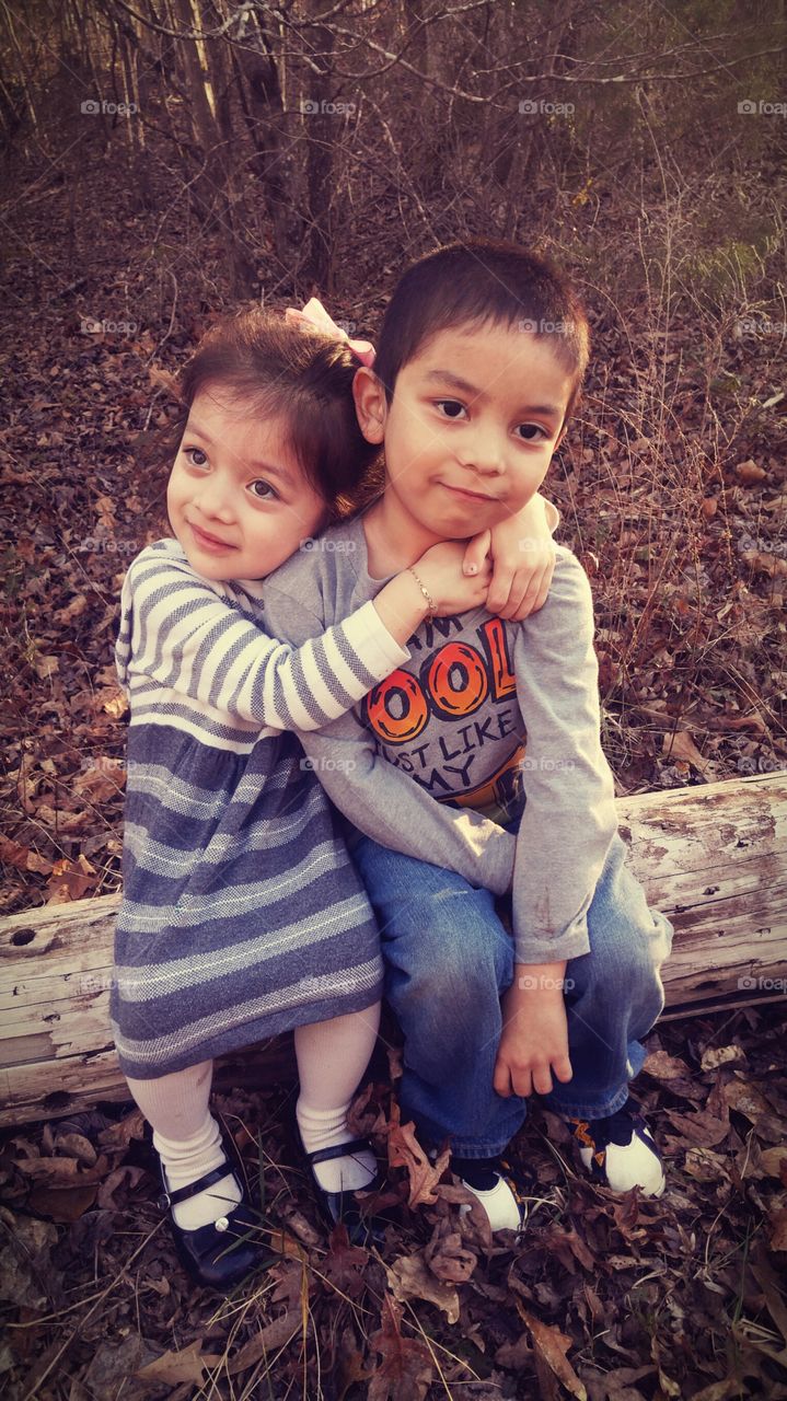 Cute brother and sister sitting on log