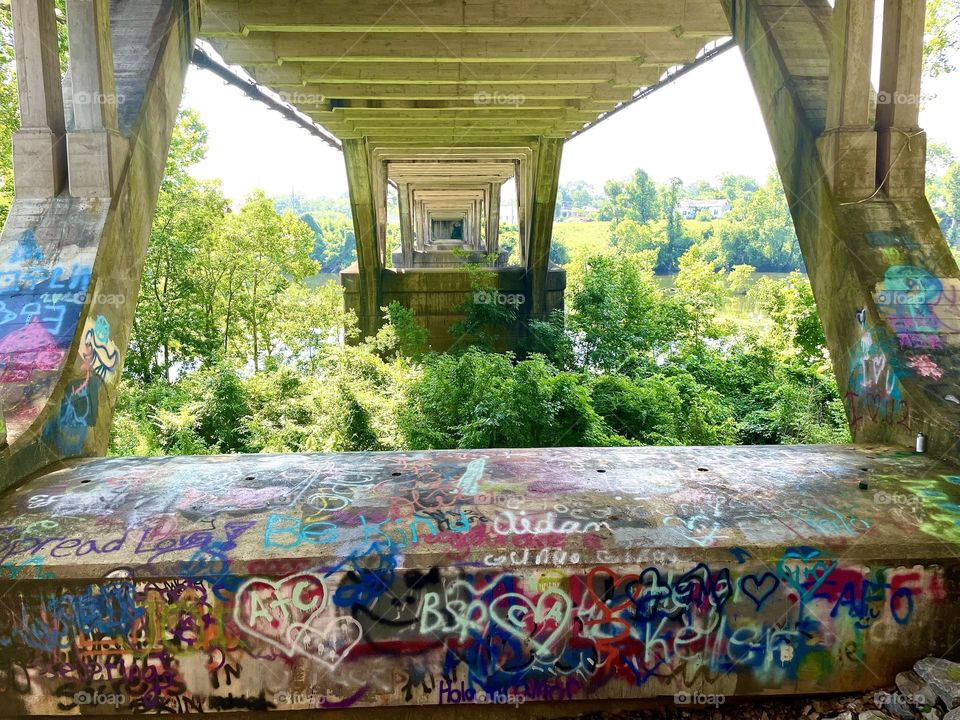 View of a bridge from underneath. Long tunnel below , graffiti splattered, sunny day